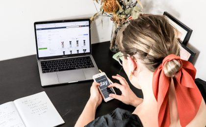 woman in orange shirt using iphone